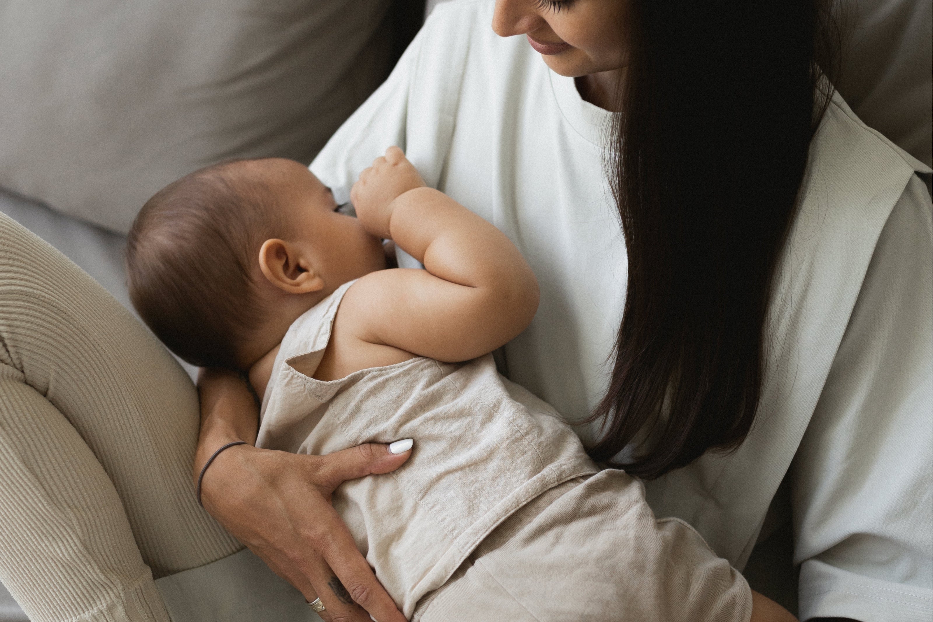 A mother breastfeeding her baby while wearing The Ultimate Tee in Dawn. The hidden nursing access makes feeding seamless and discreet, offering both comfort and style for nursing moms | Shop Online | amama.shop