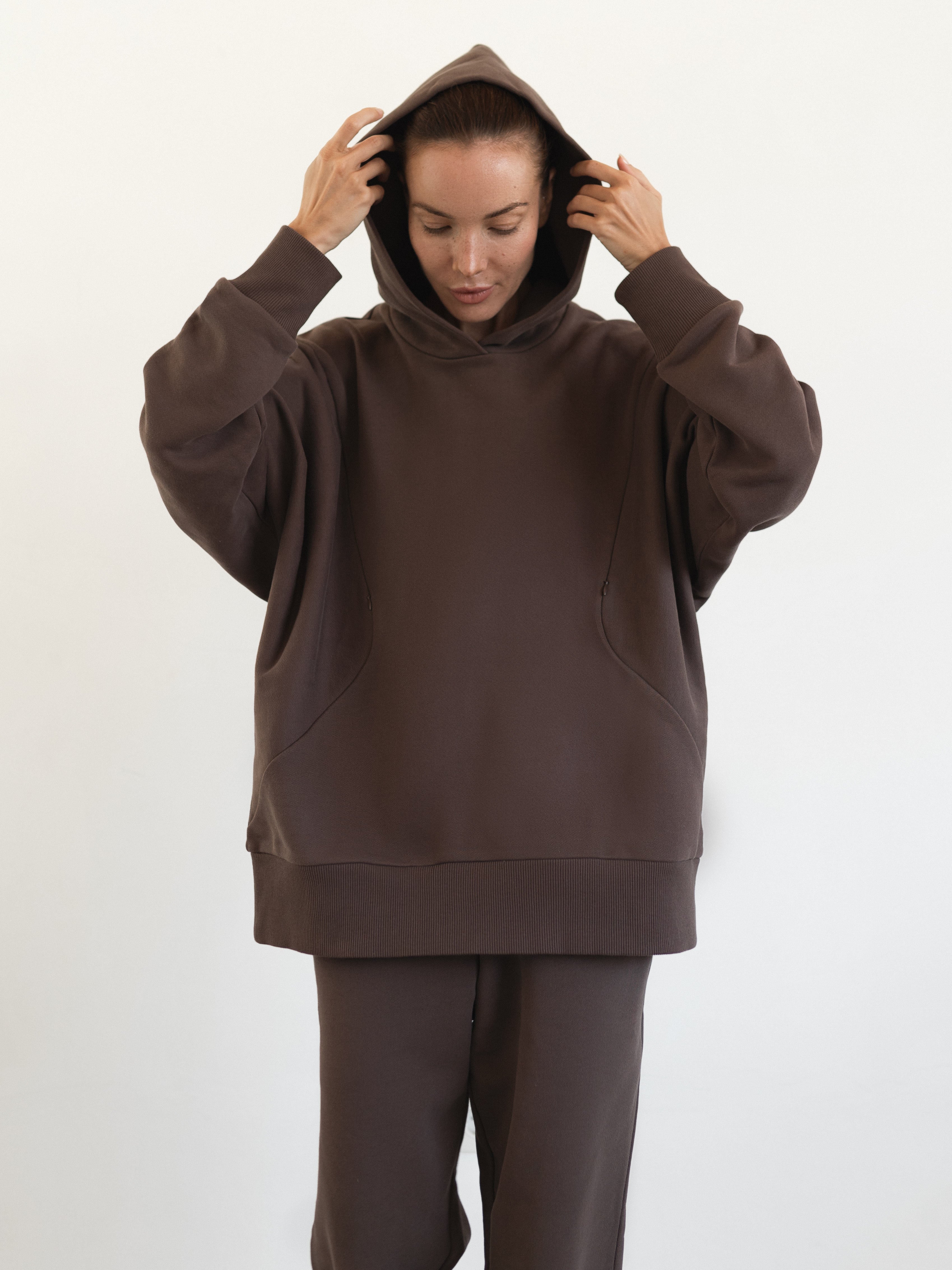 Model adjusting hood of The Optimal Hoodie in Sunset Shadow - a cozy option for maternity and breastfeeding wear | shop online | amama.shop